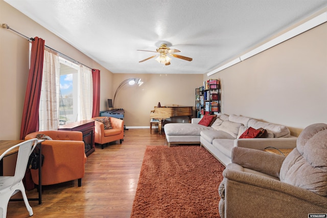 living area featuring a ceiling fan, baseboards, and wood finished floors