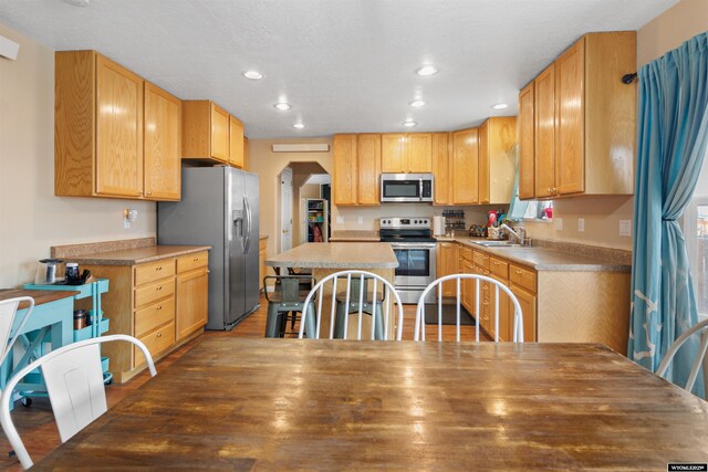 kitchen featuring a sink, arched walkways, stainless steel appliances, and recessed lighting