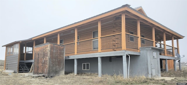 back of property featuring stairway and metal roof