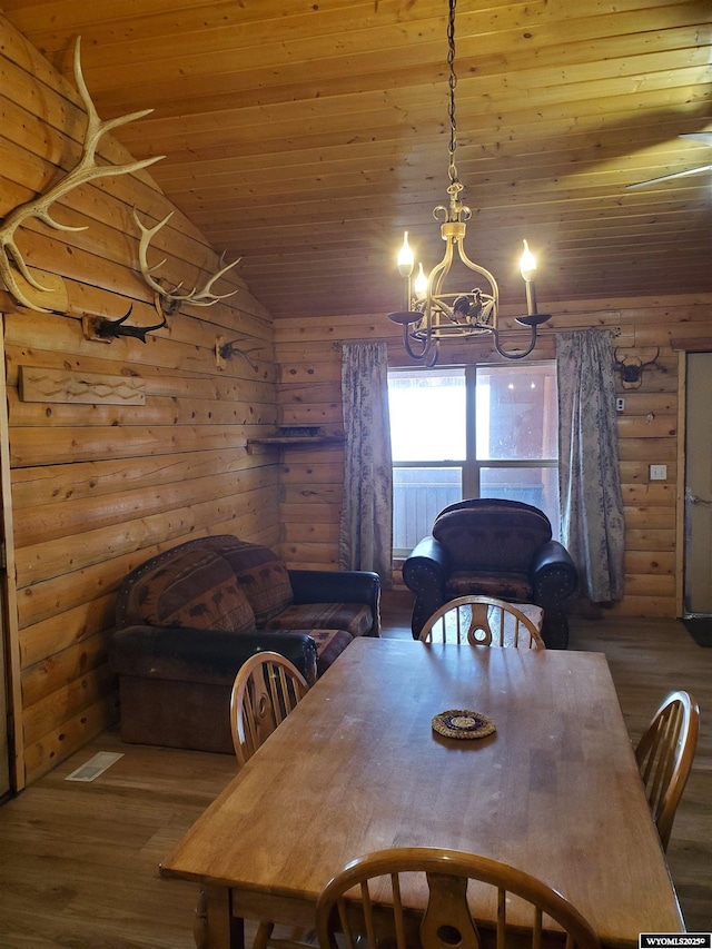 dining space with an inviting chandelier, wood ceiling, rustic walls, and wood finished floors