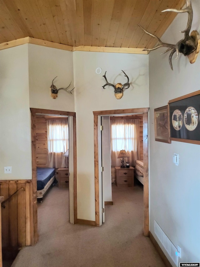 hall featuring carpet floors, visible vents, wooden ceiling, and a healthy amount of sunlight