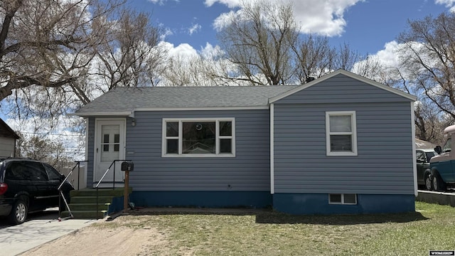 view of front of house featuring a front lawn and roof with shingles