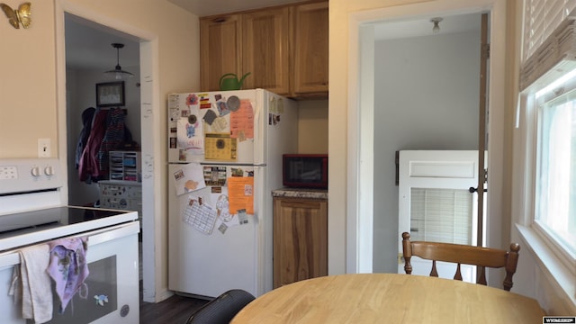 kitchen featuring light countertops, brown cabinets, white appliances, and dark wood-style floors