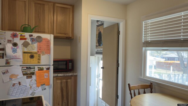 kitchen with freestanding refrigerator and brown cabinets