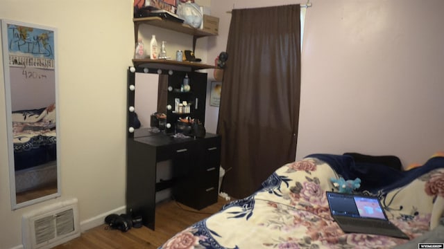 bedroom featuring visible vents, baseboards, and wood finished floors