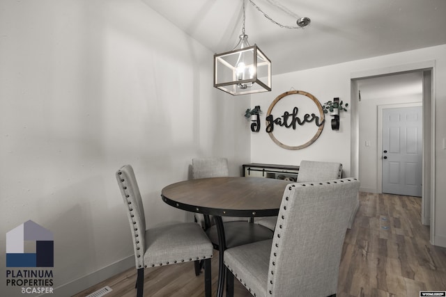 dining room with baseboards, wood finished floors, and a notable chandelier