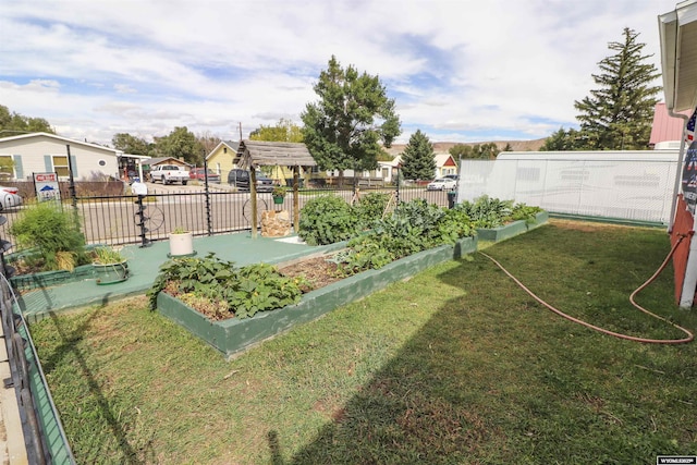 view of yard with fence, a vegetable garden, and a residential view