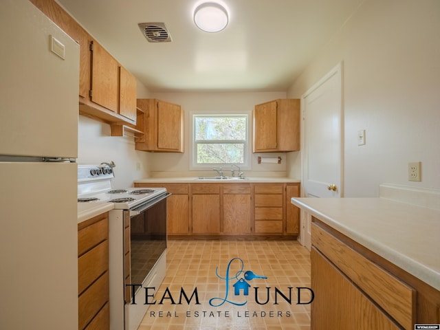 kitchen featuring visible vents, a sink, white appliances, and light countertops