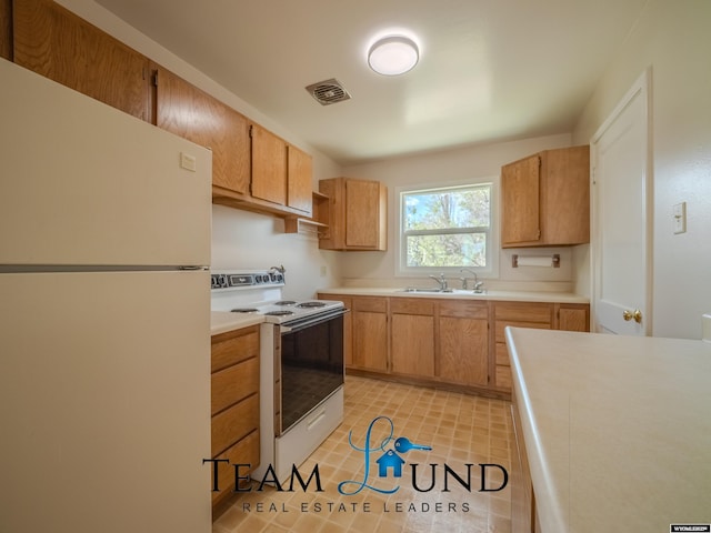kitchen with a sink, white appliances, light countertops, light tile patterned floors, and visible vents