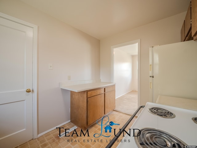 kitchen with baseboards, light countertops, brown cabinets, and white appliances