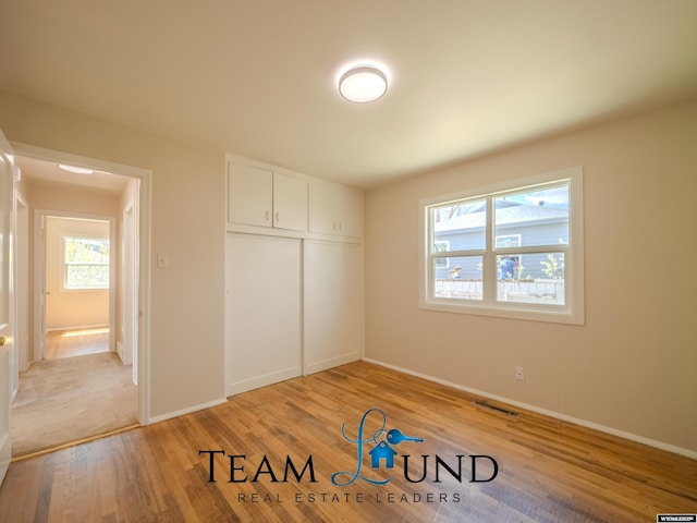 unfurnished bedroom with baseboards, visible vents, light wood-style flooring, and a closet