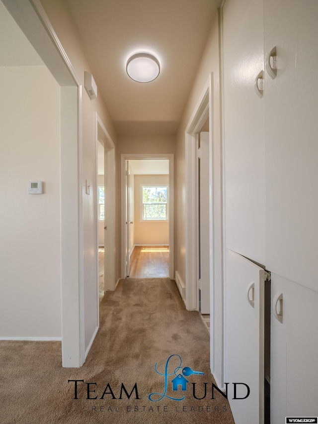 hallway with carpet floors and baseboards