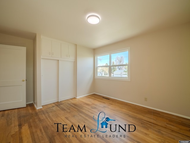 unfurnished bedroom featuring light wood-style floors, baseboards, and a closet
