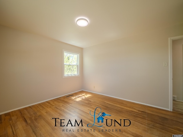spare room featuring baseboards and wood finished floors