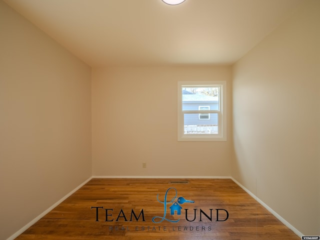 spare room with baseboards and wood finished floors
