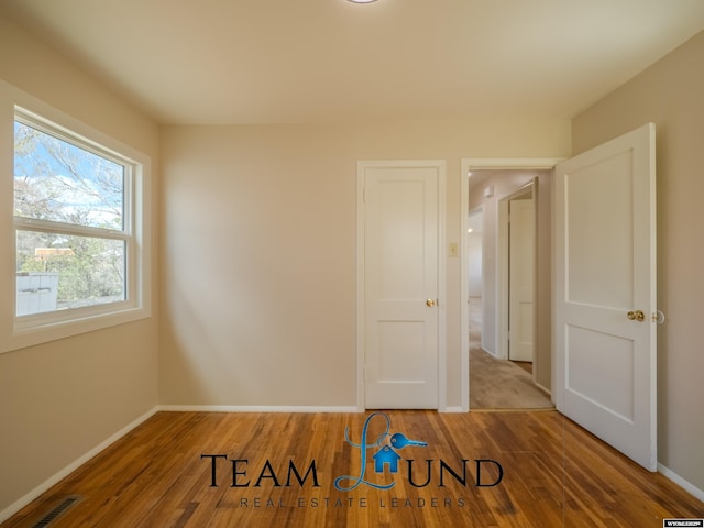 empty room with baseboards, wood finished floors, and visible vents