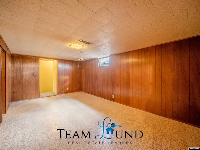 below grade area with visible vents, wood walls, and carpet