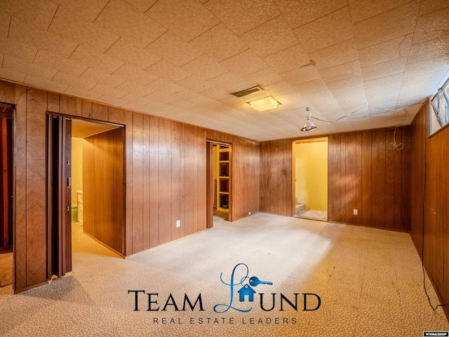 finished below grade area featuring visible vents, wood walls, and carpet
