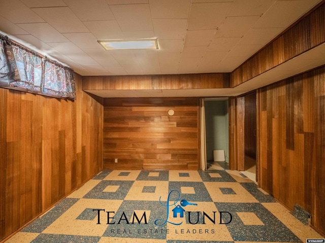 basement featuring tile patterned floors and wood walls