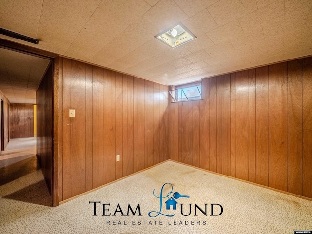 basement featuring carpet and wooden walls
