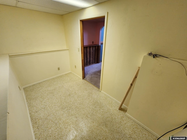 corridor featuring carpet floors, baseboards, and a paneled ceiling