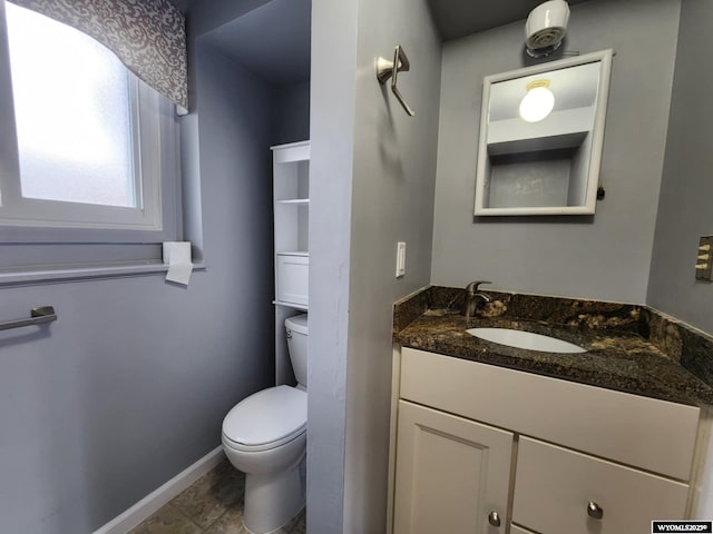 bathroom featuring toilet, baseboards, and vanity