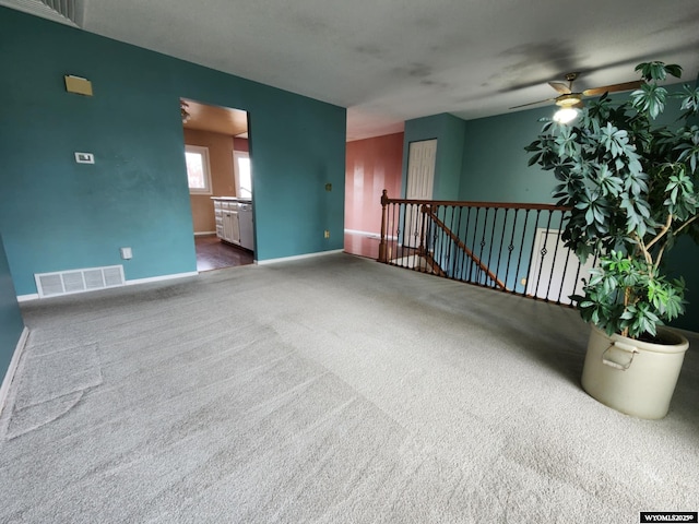 unfurnished room with carpet floors, ceiling fan, baseboards, and visible vents