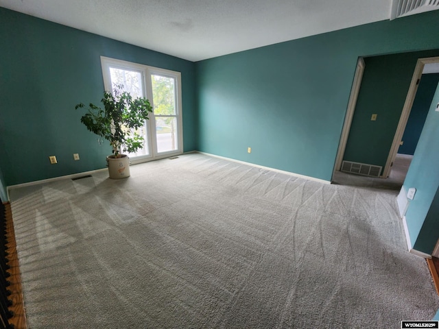 carpeted empty room with baseboards and visible vents