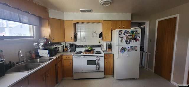 kitchen featuring brown cabinets, a sink, white appliances, backsplash, and visible vents