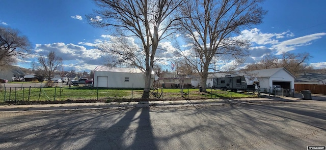 view of front facade with an attached garage, a fenced front yard, a residential view, and a front lawn