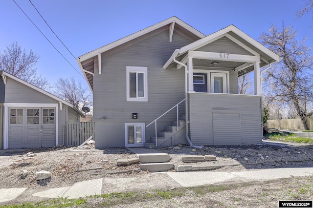 view of front of home featuring fence, an outbuilding, and stairs