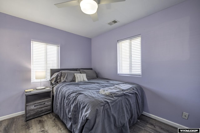 bedroom featuring baseboards, multiple windows, wood finished floors, and visible vents