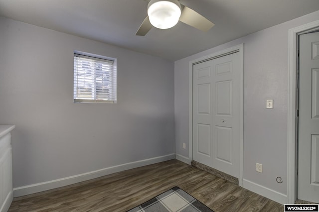 unfurnished bedroom with baseboards, ceiling fan, a closet, and dark wood-style floors