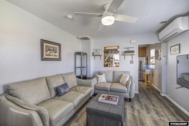 living area with ceiling fan, visible vents, a wall mounted air conditioner, wood finished floors, and baseboards