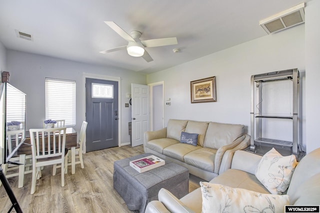 living room with a ceiling fan, visible vents, and light wood finished floors