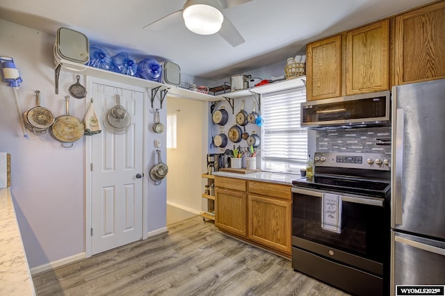 kitchen with light countertops, stainless steel appliances, brown cabinets, and light wood-style flooring