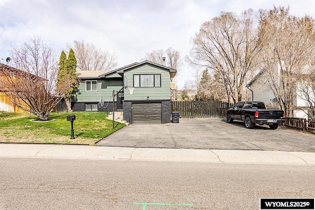 split foyer home featuring an attached garage, fence, driveway, and a front lawn