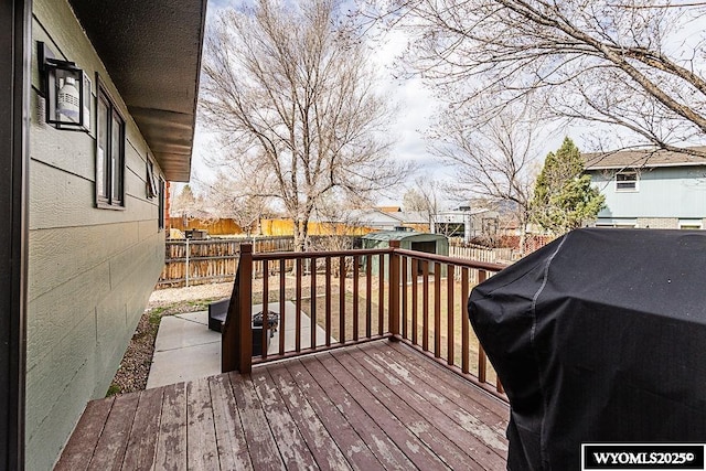 wooden terrace with a storage unit, a fenced backyard, an outbuilding, and grilling area