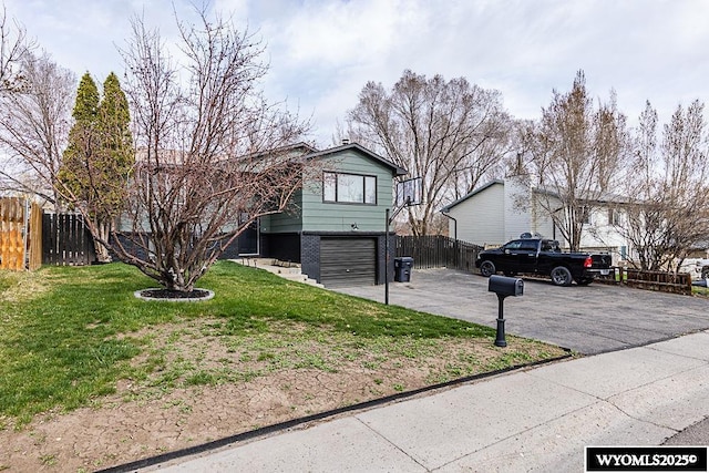 view of front of home with an attached garage, a front lawn, aphalt driveway, and fence