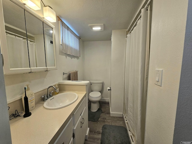 full bathroom with vanity, toilet, a textured ceiling, baseboards, and wood finished floors