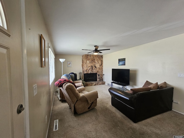 living room featuring carpet floors, a stone fireplace, plenty of natural light, a ceiling fan, and visible vents
