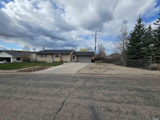 ranch-style home with a garage, fence, driveway, and a front yard