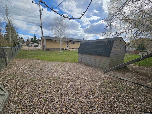 view of yard featuring an outbuilding, fence, and a storage shed