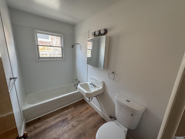 full bathroom with a sink, toilet, wood finished floors, and  shower combination
