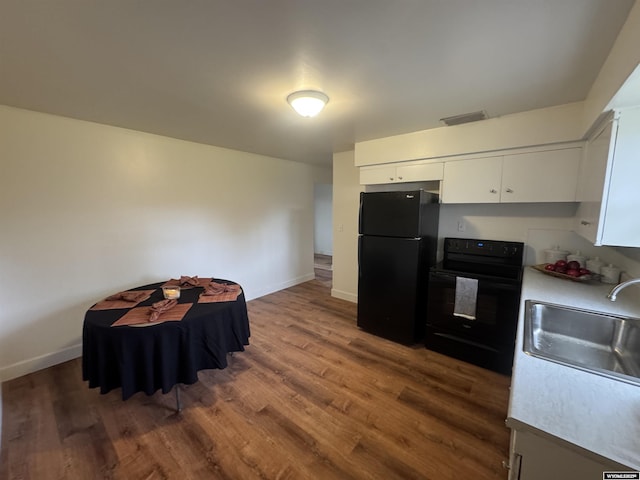 kitchen with dark wood-style flooring, visible vents, a sink, black appliances, and white cabinetry