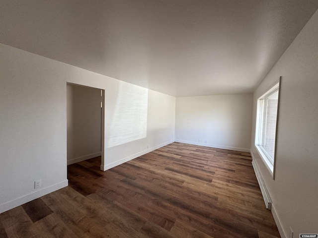 empty room with baseboards, a baseboard radiator, and dark wood-style floors