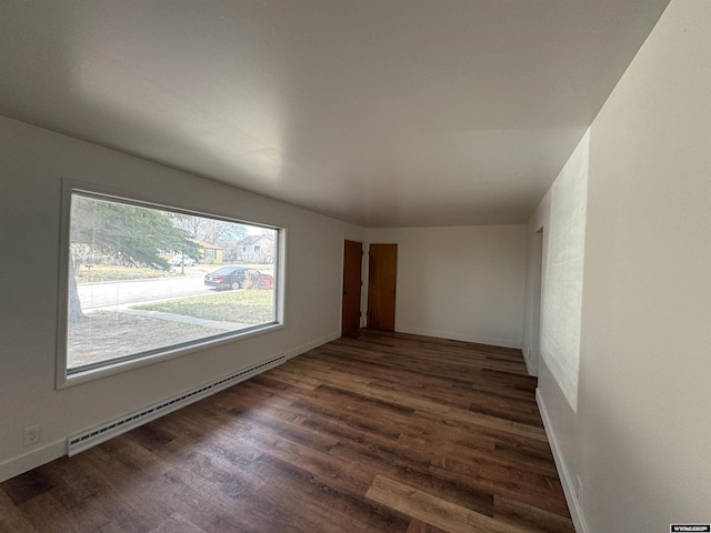 empty room featuring baseboards, baseboard heating, and wood finished floors