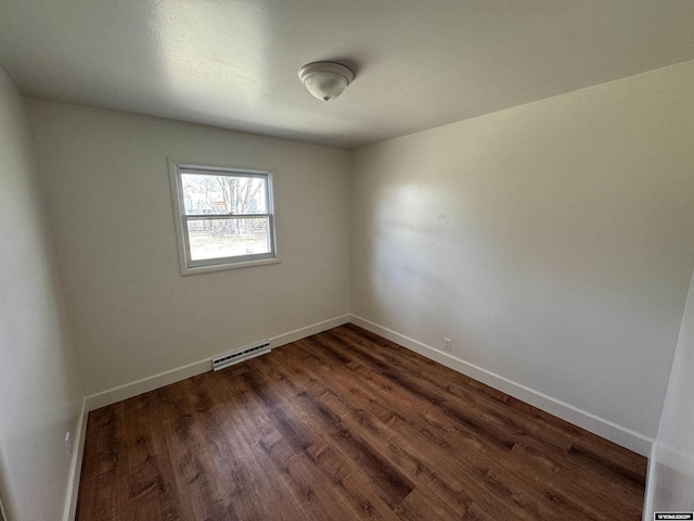 unfurnished room featuring baseboards, dark wood finished floors, and visible vents