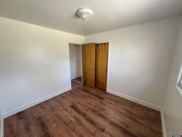 unfurnished bedroom with baseboards, a closet, and wood finished floors