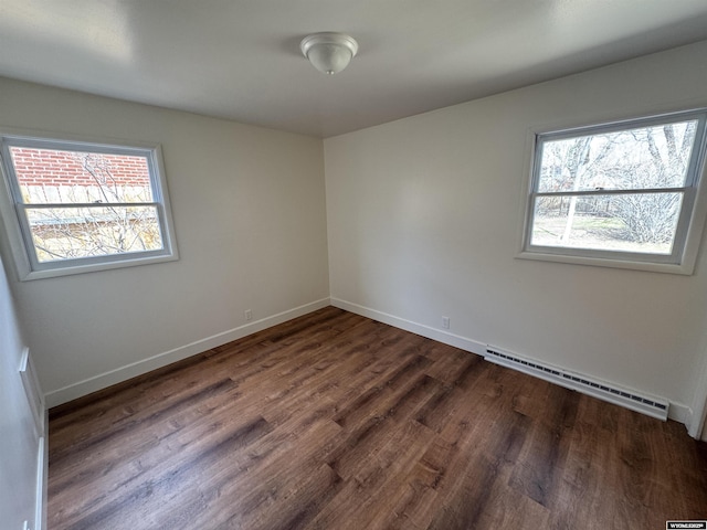empty room with baseboards, a baseboard radiator, and dark wood-style flooring